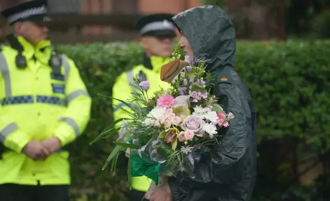 A woman brings flowers as she attends a vigil for the victims of the attack on the Heaton Park Hebrew Congregation synagogue, in Crumpsall, Manchester, England, Friday, Oct. 3, 2025, the attack happened Thursday. (AP Photo/Ian Hodgson)