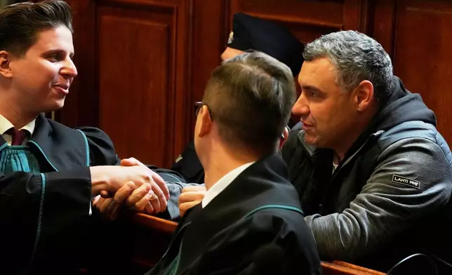 Ukrainian defendant Volodymyr Zuravlov, right, shakes hands with his lawyer Tymoteusz Paprocki, left, as a judge announce the decision not to allow for extradition to Germany in courtroom of Warsaw's Regional Court in Warsaw, Poland, Friday, Oct. 17, 2025. (AP Photo/Czarek Sokolowski)