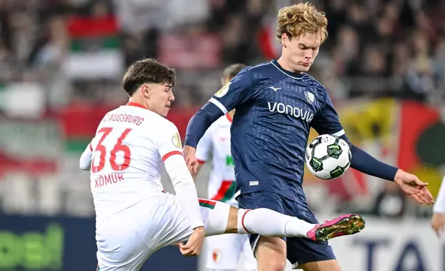 Augsburg's Mert Komur, left, and Bochum's Mats Pannewig, right, challenge for the ball during a German soccer cup second round match between FC Augsburg and VfL Bochum in Augsburg, Germany, Tuesday, Oct. 28, 2025. (Harry Langer/dpa via AP)