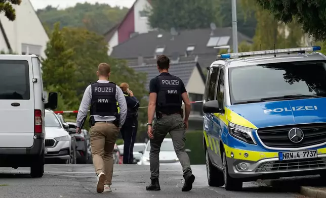 Police officers across a street in Herdecke, Germany, Tuesday, Oct. 7, 2025, after the newly elected mayor of Herdecke, Iris Stalzer, has been found critically injured in her apartment. (AP Photo/Martin Meissner)