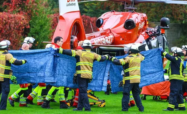 Emergency services stand next to a rescue helicopter in Herdecke, Germany, Tuesday, Oct. 7, 2025, after the newly elected mayor of Herdecke, Iris Stalzer, has been found critically injured in her apartment. (Alex Talash/dpa via AP)