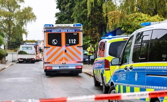 An ambulance stands in front of police cars on a street in Herdecke, Germany, Tuesday, Oct. 7, 2025, after the newly elected mayor of Herdecke, Iris Stalzer, has been found critically injured in her apartment. (Alex Talash/dpa via AP)