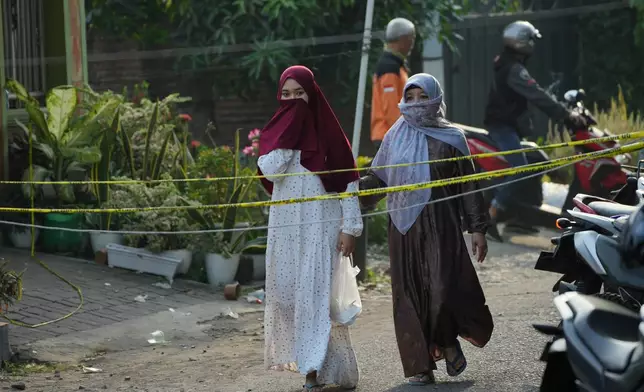 Women walk near the Islamic boarding school compound where a building collapsed, in Sidoarjo, East Java, Indonesia, Saturday, Oct. 4, 2025. (AP Photo/Achmad Ibrahim)