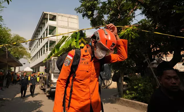 A rescuer walks near the islamic boarding school where a building collapsed in Sidoarjo, East Java, Indonesia, Saturday, Oct. 4, 2025. (AP Photo/Achmad Ibrahim)