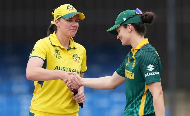 Australia's captain Tahlia McGrath, left, and South Africa's captain Laura Wolvaardt shake hands after toss during the ICC Women's Cricket World Cup match between Australia and South Africa in Indore, India, Saturday, Oct. 25, 2025. (AP Photo/Ajit Solanki)
