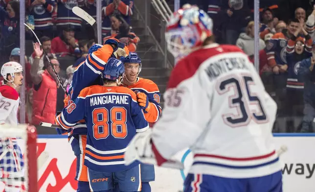 Montreal Canadiens goalie Sam Montembeault (35) looks on as Edmonton Oilers' Darnell Nurse (25), Andrew Mangiapane (88) and Connor McDavid (97) celebrate a goal during second period NHL action, in Edmonton on Thursday, Oct. 23, 2025. (Jason Franson/The Canadian Press via AP)