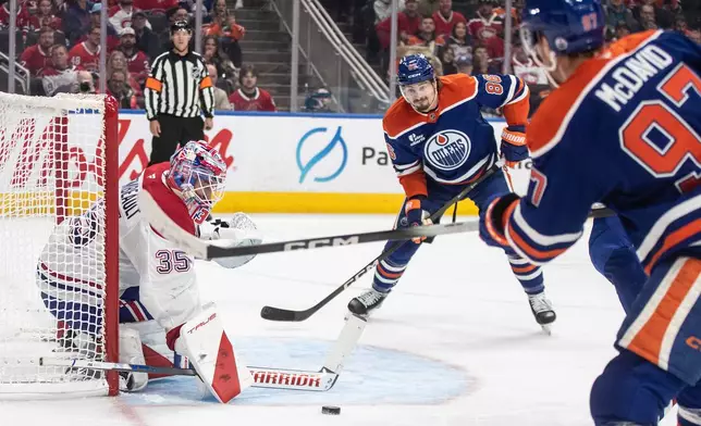 Montreal Canadiens goalie Sam Montembeault (35) makes the save on Edmonton Oilers' Connor McDavid (97) as David Tomasek (86) looks for the rebound during second period NHL action, in Edmonton on Thursday, Oct. 23, 2025.(Jason Franson/The Canadian Press via AP)