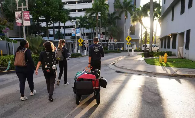 Malachi Peterson-Hester, right, pulls a cart with medical supplies as the Miami Street Medicine team heads out to provide medical services to homeless people, Saturday, Sept. 20, 2025, in Miami. (AP Photo/Lynne Sladky)