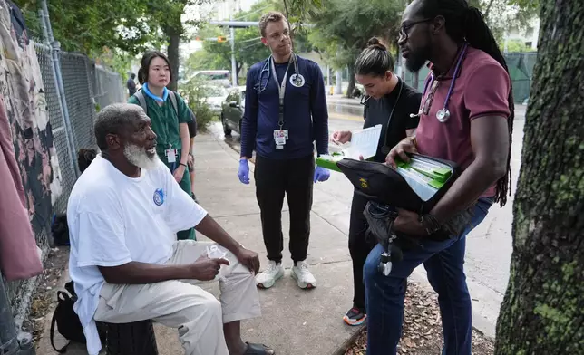 Dr. Inaki Bent, right, talks with Jonas Richards, left, while working with the Miami Street Medicine team to provide medical services to homeless people, Saturday, Aug. 23, 2025, in Miami. (AP Photo/Lynne Sladky)