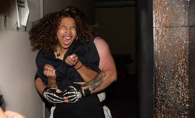 Rosey Washington reacts while being grabbed during her performance at the Erebus Haunted House, Oct. 2, 2025, in Pontiac, Mich. (AP Photo/Ryan Sun)