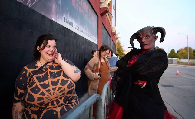 Renee Piehl, right, interacts with people waiting in line at the Erebus Haunted House, Oct. 2, 2025, in Pontiac, Mich. (AP Photo/Ryan Sun)