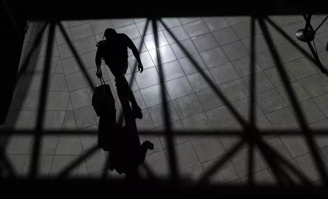 A traveler walks through the Baltimore/Washington International Thurgood Marshall Airport, Thursday, Oct. 2, 2025, in Baltimore. (AP Photo/Stephanie Scarbrough)