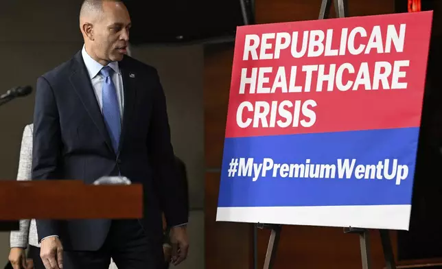 House Minority Leader Hakeem Jeffries, D-N.Y., passes a sign on a stage that the House Democratic leaders held a news conference on the 8th day of government shutdown at the U.S. Capitol on Wednesday, Oct. 8, 2025, in Washington. (AP Photo/John McDonnell)