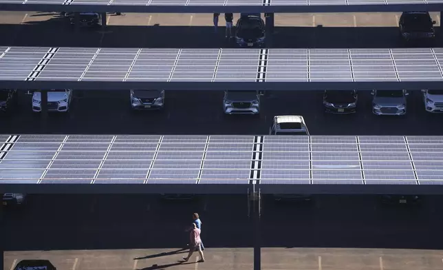 People walk though a parking lot with solar panels near Lincoln Financial Field on Monday, Sept. 8, 2025, in Philadelphia. (AP Photo/Matt Slocum)