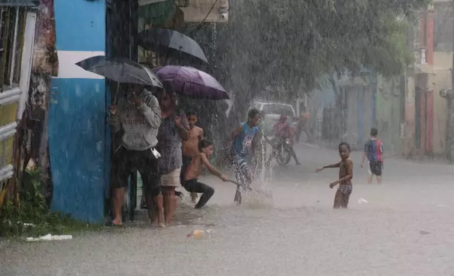 Children play in a street flooded by rains caused by Tropical Storm Melissa in Santo Domingo, Dominican Republic, Friday, Oct. 24, 2025. (AP Photo/Ricardo Hernandez)