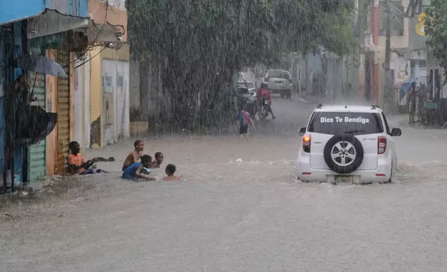 Children play in a street flooded by rains caused by Tropical Storm Melissa in Santo Domingo, Dominican Republic, Friday, Oct. 24, 2025. (AP Photo/Ricardo Hernandez)