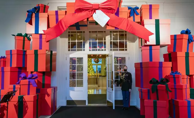 FILE - A Marine White House military social aide holds the door to the East Wing entrance of the White House during a press preview of the White House holiday decorations, Nov. 29, 2021, in Washington. (AP Photo/Evan Vucci, File)