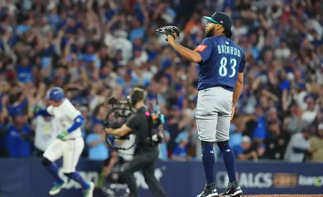 Seattle Mariners pitcher Eduard Bazardo (83) looks on as Toronto Blue Jays' George Springer, back left, rounds the bases after hitting a three-run home run during the seventh inning in Game 7 of baseball's American League Championship Series in Toronto, Monday, Oct. 20, 2025. (Frank Gunn/The Canadian Press via AP)