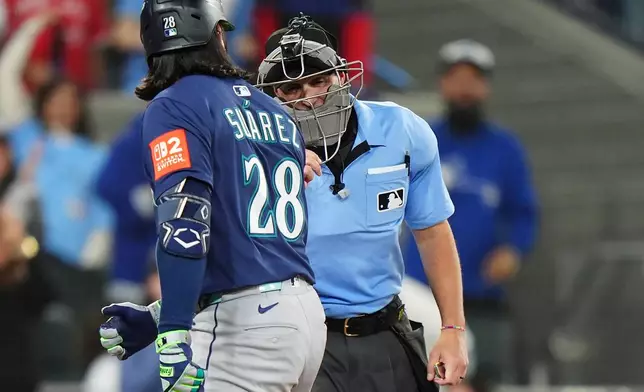 Seattle Mariners' Eugenio Suárez (28) argues with home plate umpire Quinn Wolcott, right, during the eighth inning in Game 7 of baseball's American League Championship Series against the Toronto Blue Jays in Toronto, Monday, Oct. 20, 2025. (Frank Gunn/The Canadian Press via AP)
