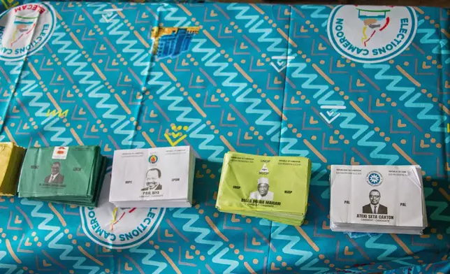 Stacks of ballot papers bearing the faces of presidential candidates are displayed on a table at a polling station before voting begins in Garoua, Cameroon, Sunday, Oct. 12, 2025.(AP Photo/Welba Yamo Pascal)