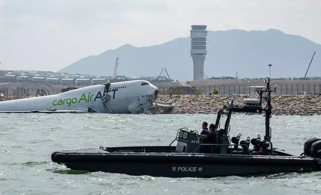 Police officers on a boat patrol near a cargo aircraft that skidded off a Hong Kong runway on Monday, Oct. 20, 2025. (AP Photo/Chan Long Hei)