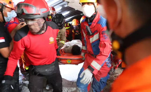 Rescuers carry a survivor who was pulled out from the rubble after a building under construction collapsed at an Islamic boarding school in Sidoarjo, East Java, Indonesia, Wednesday, Oct. 1, 2025. (AP Photo/Alam Syahirul)