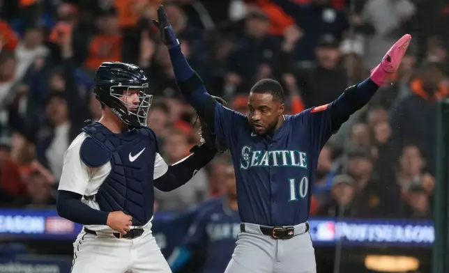 Seattle Mariners' Victor Robles (10) celebrates after scoring past Detroit Tigers catcher Dillon Dingler, left, during the third inning in Game 3 of baseball's American League Division Series Tuesday, Oct. 7, 2025, in Detroit. (AP Photo/Ryan Sun)