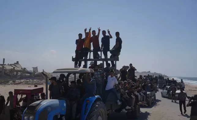 Displaced Palestinians ride on tractors and vehicles loaded with people and belongings along the coastal road near Wadi Gaza in the central Gaza Strip, moving toward Gaza City, Friday, Oct. 10, 2025, after Israel and Hamas agreed to a pause in their war and the release of the remaining hostages. (AP Photo/Abdel Kareem Hana)