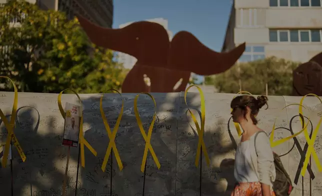 A person walks past an installation simulating a tunnel in Gaza in an act of solidarity with hostages believed to be held underground by Hamas during the Jewish holiday of Sukkot, at a plaza known as hostages square, in Tel Aviv, Israel, Friday, Oct. 10, 2025. (AP Photo/Francisco Seco)