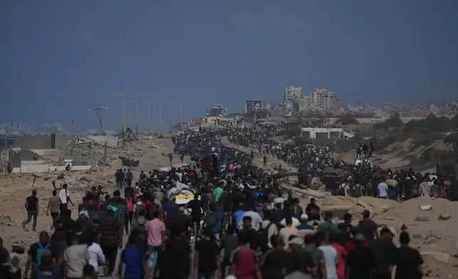 Displaced Palestinians walk with their belongings along the coastal road near Wadi Gaza in the central Gaza Strip, moving toward Gaza City, Friday, Oct. 10, 2025, after Israel and Hamas have agreed to a pause in their war and the release of the remaining hostages. (AP Photo/Abdel Kareem Hana)