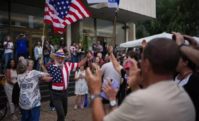 People dance as they celebrate following the announcement that Israel and Hamas have agreed to the first phase of a peace plan to pause the fighting, at a plaza known as hostages square in Tel Aviv, Israel, Thursday, Oct. 9, 2025. (AP Photo/Emilio Morenatti)