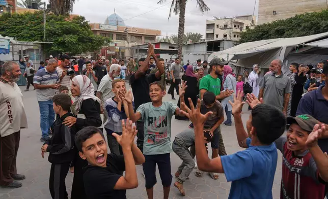 Palestinians celebrate following the announcement that Israel and Hamas have agreed to the first phase of a peace plan to pause the fighting, outside Al-Aqsa Hospital in Deir al-Balah, central Gaza Strip, Thursday, Oct. 9, 2025. (AP Photo/Abdel Kareem Hana)