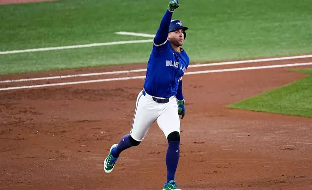 Toronto Blue Jays George Springer celebrates as he runs the bases after hitting a solo home run against the Seattle Mariners during the first inning in Game 1 of baseball's American League Championship Series, Sunday, Oct. 12, 2025, in Toronto. (AP Photo/David J. Phillip)