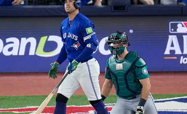 Toronto Blue Jays' George Springer watches his solo home run take flight as Seattle Mariners catcher Cal Raleigh looks on during the first inning in Game 1 of baseball's American League Championship Series, Sunday, Oct. 12, 2025, in Toronto. (AP Photo/David J. Phillip)