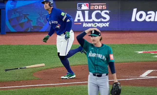 Toronto Blue Jays George Springer, left, watches his solo home run take flight as Seattle Mariners pitcher Bryce Miller looks on during the first inning in Game 1 of baseball's American League Championship Series, Sunday, Oct. 12, 2025, in Toronto. (AP Photo/David J. Phillip)
