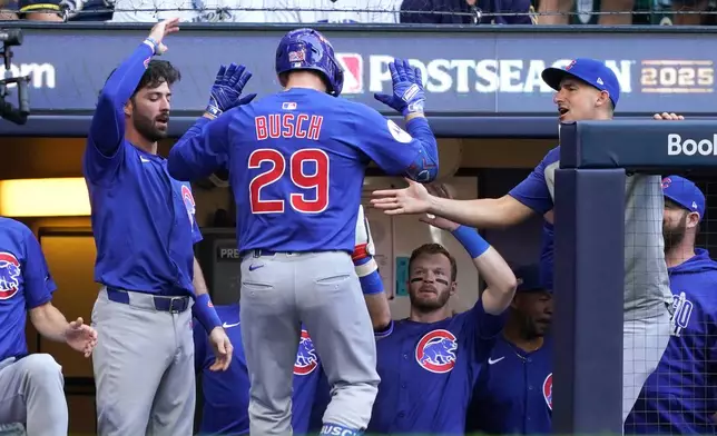 Chicago Cubs' Michael Busch (29) high-fives teammates after hitting a home run during the first inning in Game 1 of baseball's National League Division Series against the Milwaukee Brewers, Saturday, Oct. 4, 2025, in Milwaukee. (AP Photo/Kayla Wolf)