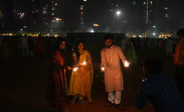 Friends light the fire crackers during the Diwali festival of lights in Mumbai, India, on Monday, Oct. 20, 2025. (AP Photo/Rafiq Maqbool)