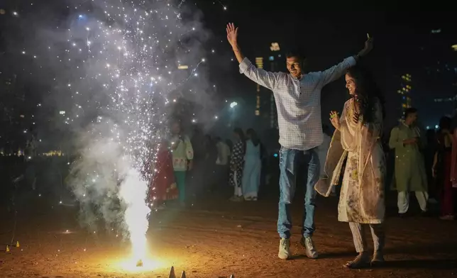 A family lights firecrackers during the Diwali festival of lights in Mumbai, India, Monday, Oct. 20, 2025. (AP Photo/Rafiq Maqbool)