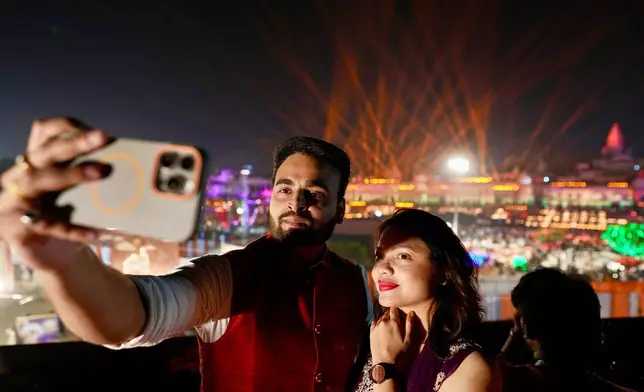 A couple takes a selfie along the Saryu river during Deepotsav celebrations on the eve of Diwali in Ayodhya, India, Sunday, Oct. 19, 2025. (AP Photo/Rajesh Kumar Singh)
