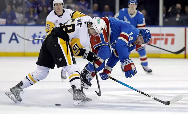 Pittsburgh Penguins defenseman Kris Letang (58) checks New York Rangers right wing Taylor Raddysh (14) off the puck in the second period of an NHL hockey game Tuesday, Oct. 7, 2025, in New York. (AP Photo/Adam Hunger)
