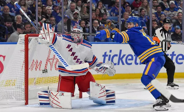 New York Rangers goalie Igor Shesterkin, left, and Buffalo Sabres left wing Jason Zucker reach for the puck during the second period of an NHL hockey game in Buffalo, N.Y., Thursday, Oct. 9, 2025. (AP Photo/Adrian Kraus)