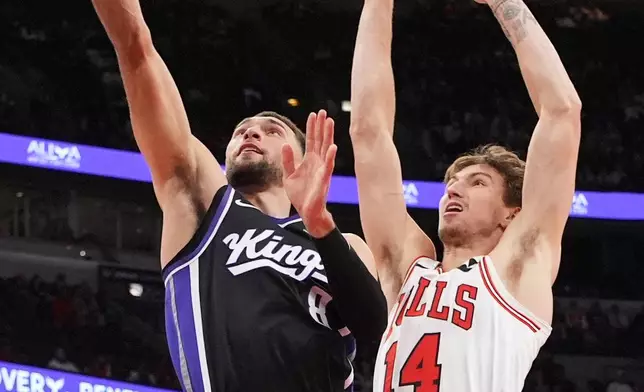 Sacramento Kings guard Zach Lavine, left, drives to the basket past Chicago Bulls forward Matas Buzelis during the first half of an NBA basketball game in Chicago, Wednesday, Oct. 29, 2025. (AP Photo/Nam Y. Huh)