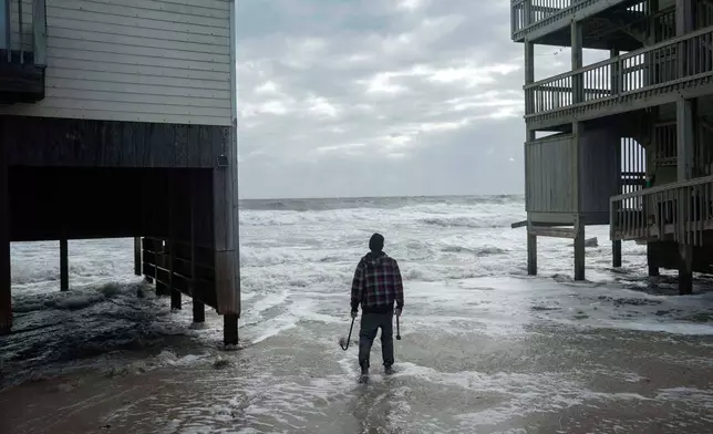 A worker who is reinforcing a home at risk of falling into the ocean looks out toward the waves as a storm approaches Friday, Oct. 10, 2025, in Buxton, N.C. (AP Photo/Allison Joyce)
