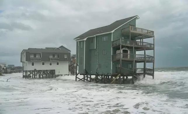 Homes at risk of falling into the ocean are visible as a storm approaches Friday, Oct. 10, 2025, in Buxton, N.C. (AP Photo/Allison Joyce)