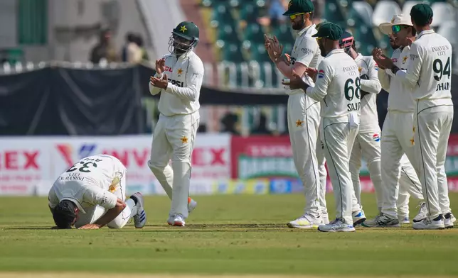 Pakistan's Asif Afridi, left, performs Sajdah, a prayer bow in gratitude to God, as teammates clapping after he took his fifty wicket to dismiss South Africa's Simon Harmer during the third day of the second test cricket match between Pakistan and South Africa, in Rawalpindi, Pakistan, Wednesday, Oct. 22, 2025. (AP Photo/Anjum Naveed)