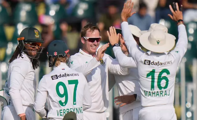 South Africa's Simon Harmer, center, celebrates with teammates after takin the wicket of Pakistan's Shan Masood during the third day of the second test cricket match between Pakistan and South Africa, in Rawalpindi, Pakistan, Wednesday, Oct. 22, 2025. (AP Photo/Anjum Naveed)