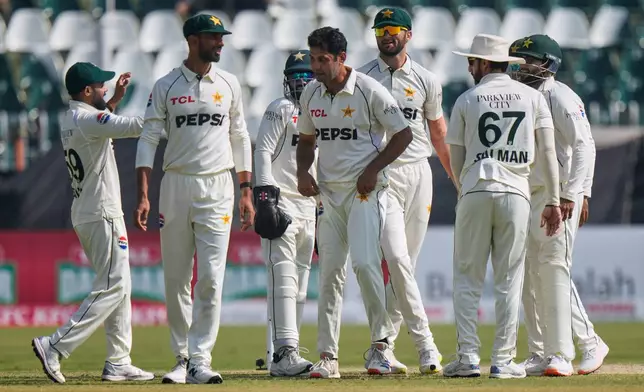 Pakistan's Asif Afridi, center, is congratulated by teammates after taking his fifty wicket to dismiss South Africa's Simon Harmer during the third day of the second test cricket match between Pakistan and South Africa, in Rawalpindi, Pakistan, Wednesday, Oct. 22, 2025. (AP Photo/Anjum Naveed)