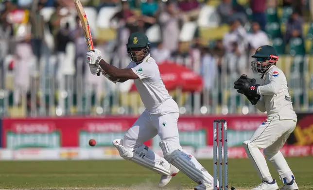 South Africa's Kagiso Rabada, left, plays a shot as Pakistan's Mohammad Rizwan watches during the third day of the second test cricket match between Pakistan and South Africa, in Rawalpindi, Pakistan, Wednesday, Oct. 22, 2025. (AP Photo/Anjum Naveed)