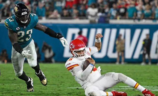Kansas City Chiefs quarterback Patrick Mahomes slides past Jacksonville Jaguars linebacker Foyesade Oluokun (23) for a first down during the second half of an NFL football game against the Jacksonville Jaguars, Monday, Oct. 6, 2025, in Jacksonville, Fla. (AP Photo/Phelan M. Ebenhack)