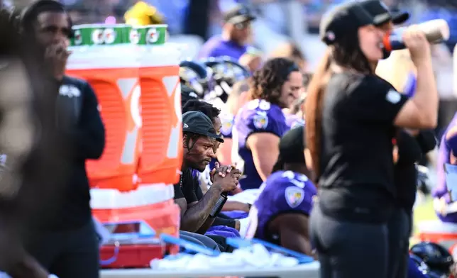 Baltimore Ravens quarterback Lamar Jackson, center, sits on the sideline during the second half of an NFL football game against the Houston Texans, Sunday, Oct. 5, 2025, in Baltimore. (AP Photo/Nick Wass)